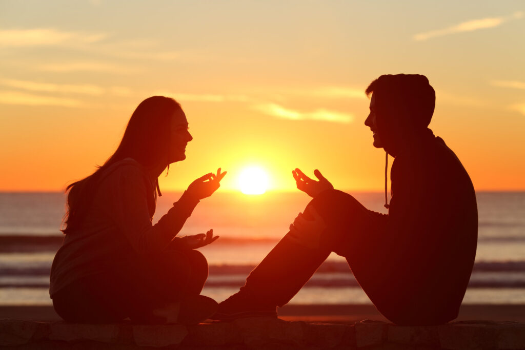 Two students talking at sunset on the beach in Hua Hin, Thailand, during Dragon Study Tours Residential English Camp, highlighting communication and connection.