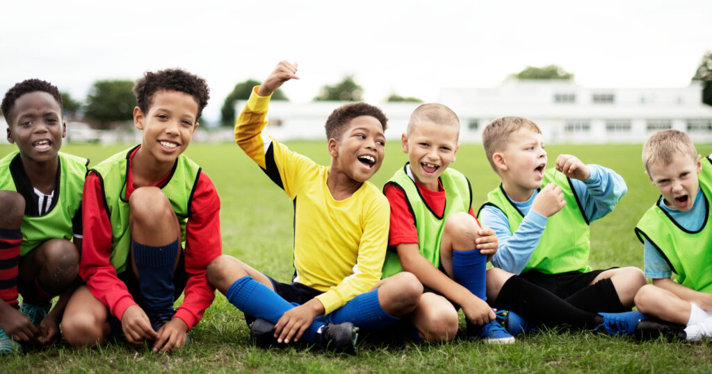 Young football players smiling and celebrating during training at the Residential Football English Camp in Hua Hin, Thailand, part of the Dragon Study Tours Premier League Review week.