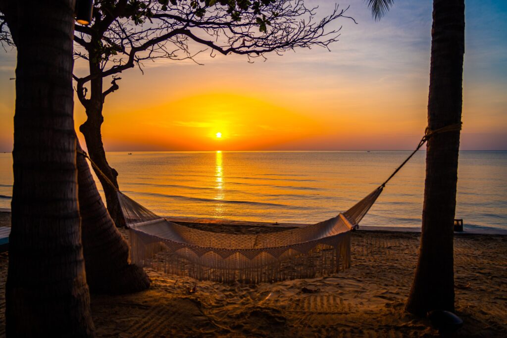 Learn English in Thailand at Hua Hin Beach during sunset, where students relax in a hammock overlooking the calm sea after a day of study with Dragon Study Tours.