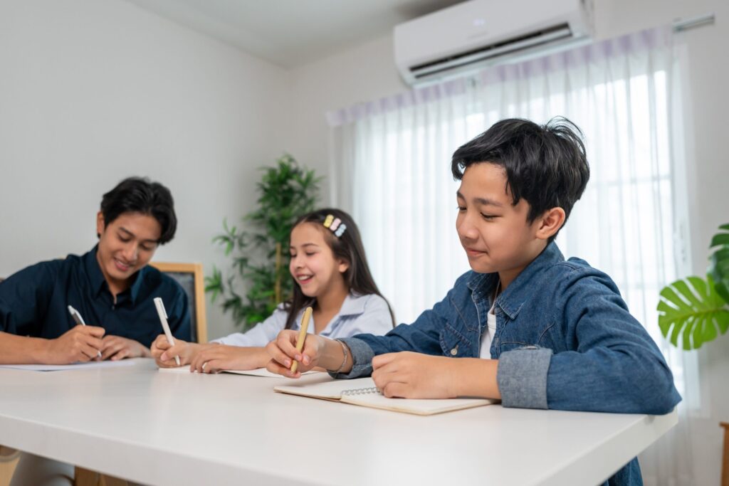 Thai students practising speaking and writing skills during a Trinity GESE Grade 4 lesson at Dragon Study Tours, showing how young learners Learn English in Thailand with confidence.